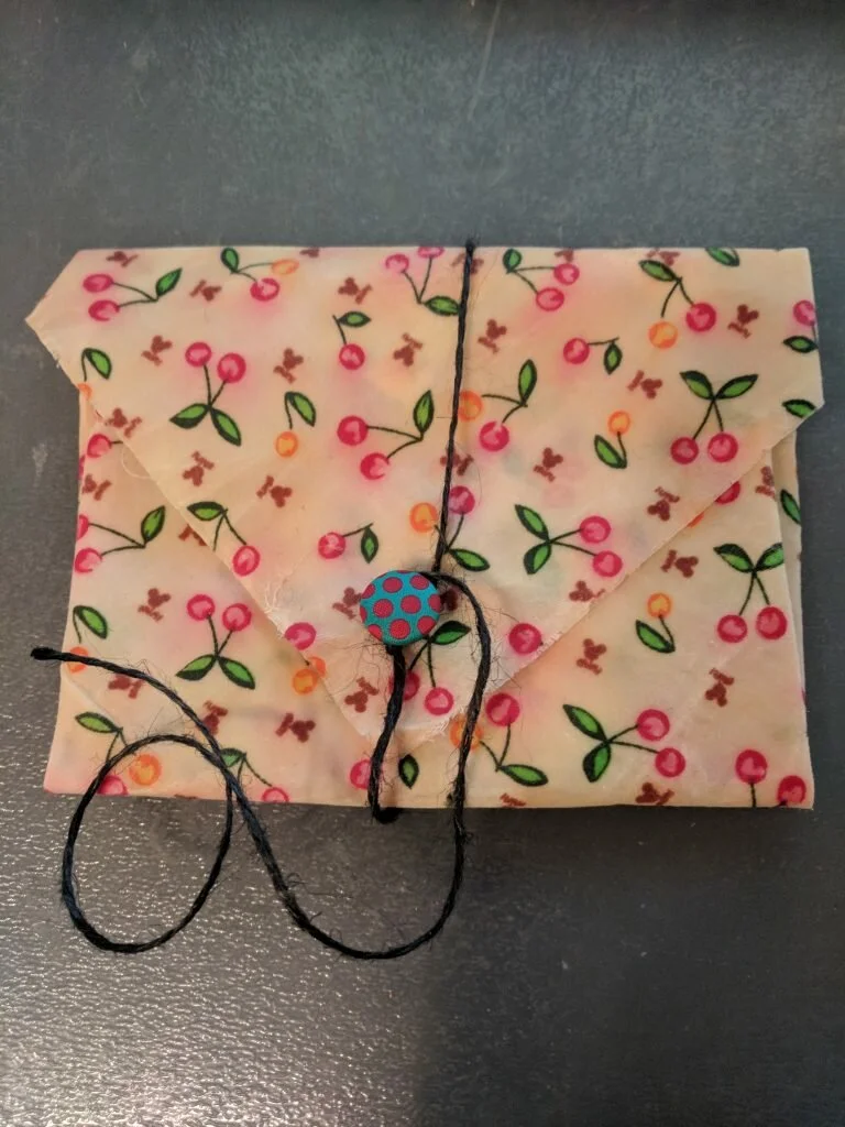 a beeswax wrap transformed into a sandwhich wrap with a button closure and a string