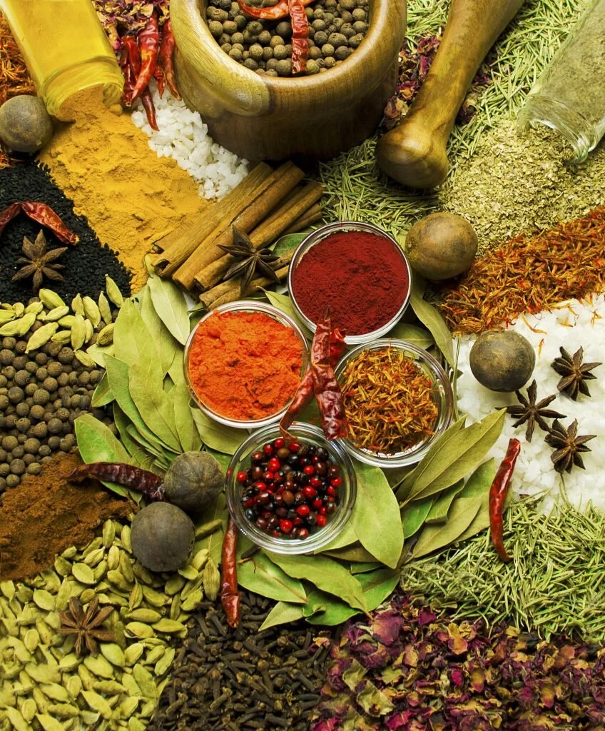 a table full of different spices, cinnamon, turmeric, cardamon, chili, star anis, bay leaf, etc.